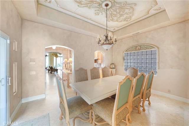 dining space featuring a towering ceiling and a raised ceiling