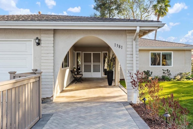 entrance to property with a garage and a lawn