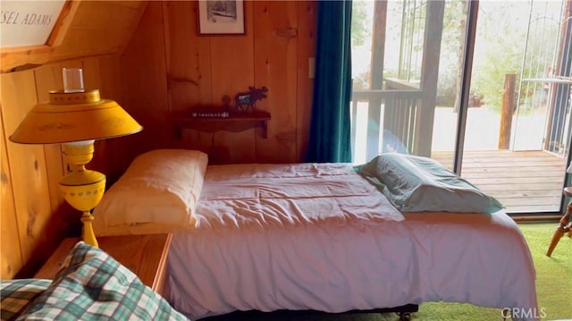 bedroom featuring access to outside, carpet flooring, vaulted ceiling, and wood walls