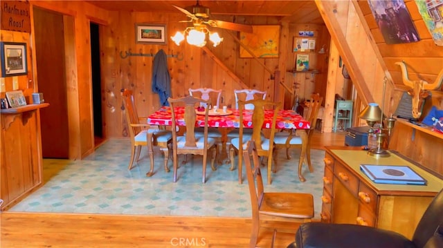 dining area with ceiling fan, light hardwood / wood-style floors, and wood walls