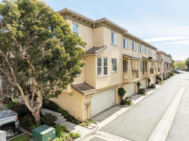 view of property featuring an attached garage, a residential view, and concrete driveway