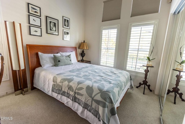 bedroom featuring baseboards, multiple windows, and light colored carpet