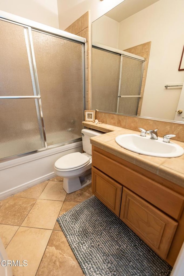 full bathroom with bath / shower combo with glass door, vanity, toilet, and tile patterned floors