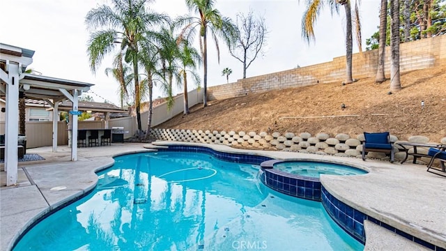 view of pool featuring an in ground hot tub, area for grilling, an outdoor bar, and a patio area