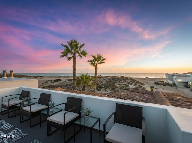 balcony at dusk with a beach view and a water view