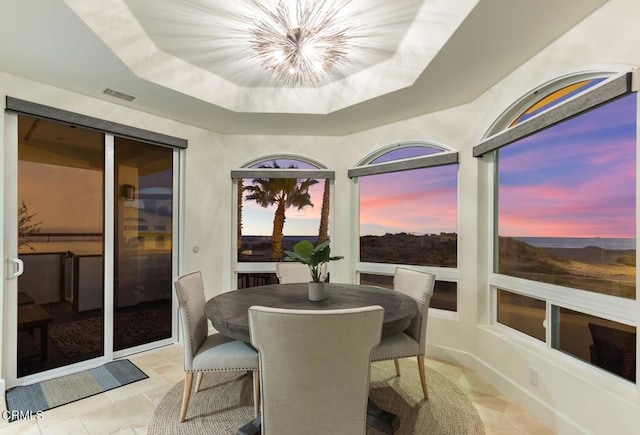 sunroom / solarium featuring a raised ceiling and a chandelier