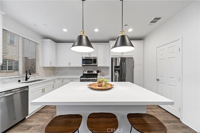 kitchen with appliances with stainless steel finishes, decorative light fixtures, a kitchen breakfast bar, and a kitchen island