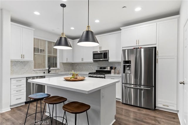 kitchen featuring pendant lighting, white cabinetry, appliances with stainless steel finishes, and a center island