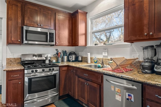 kitchen featuring light stone counters, appliances with stainless steel finishes, and sink