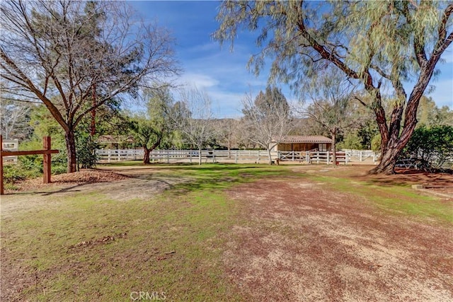 view of yard featuring an outbuilding, an exterior structure, fence, and a rural view