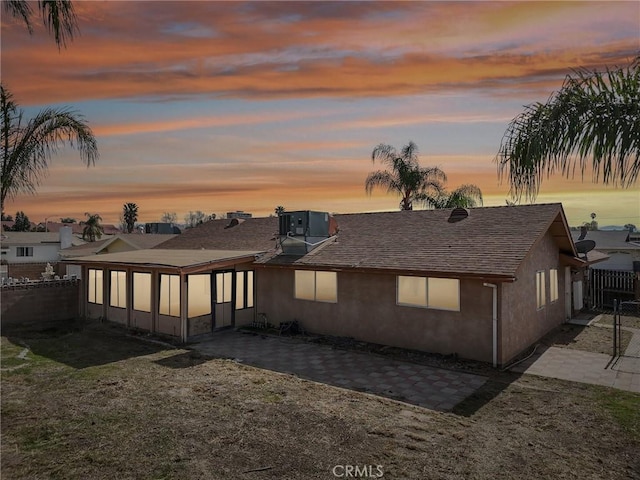 back house at dusk with cooling unit, a yard, and a patio area