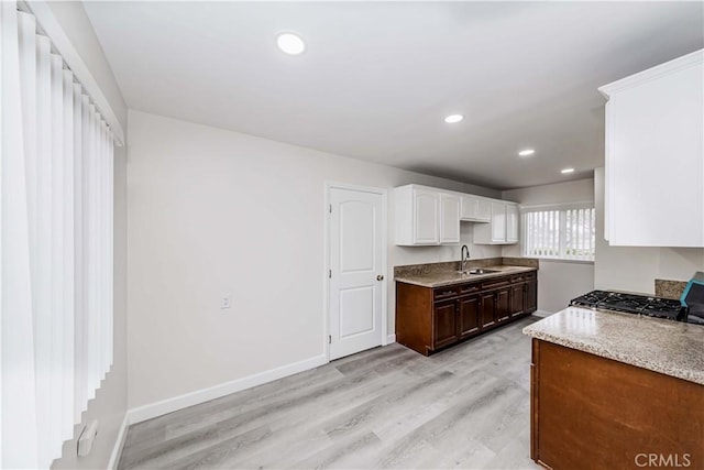 kitchen featuring white cabinetry, sink, stove, and light wood-type flooring