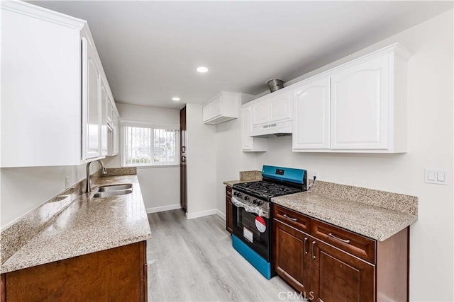 kitchen featuring sink, gas range, light hardwood / wood-style flooring, and white cabinets