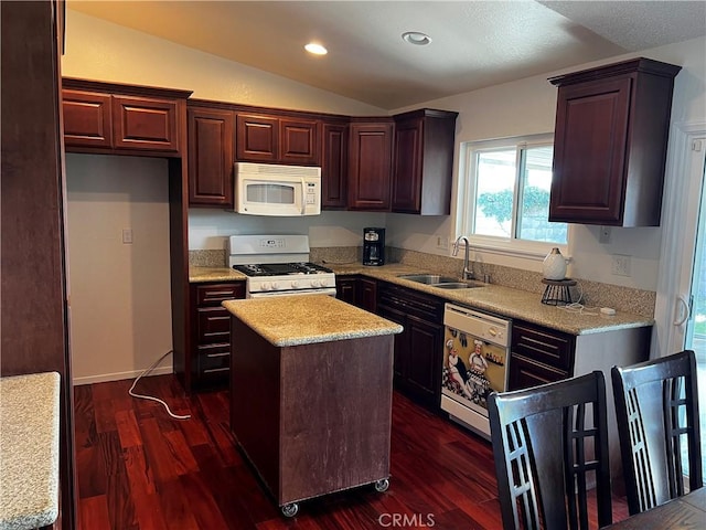 kitchen with sink, vaulted ceiling, dark hardwood / wood-style flooring, a kitchen island, and white appliances