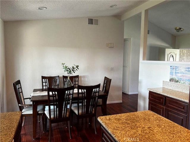 dining room with lofted ceiling, dark wood-type flooring, and a textured ceiling