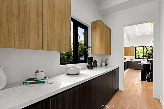 kitchen with a wealth of natural light, light stone countertops, and light wood-type flooring