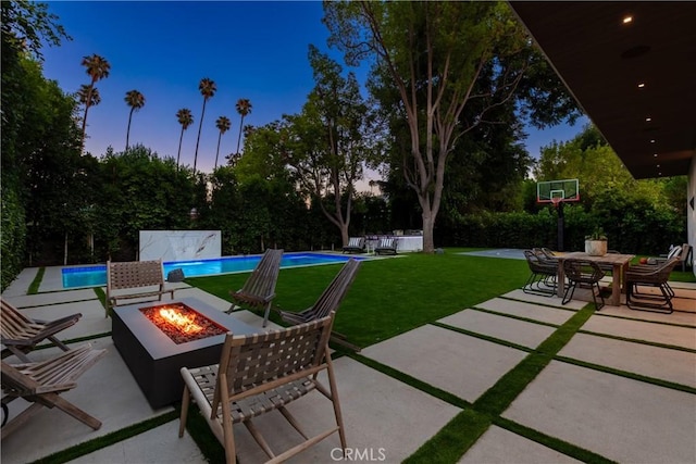 patio terrace at dusk featuring a lawn and an outdoor fire pit