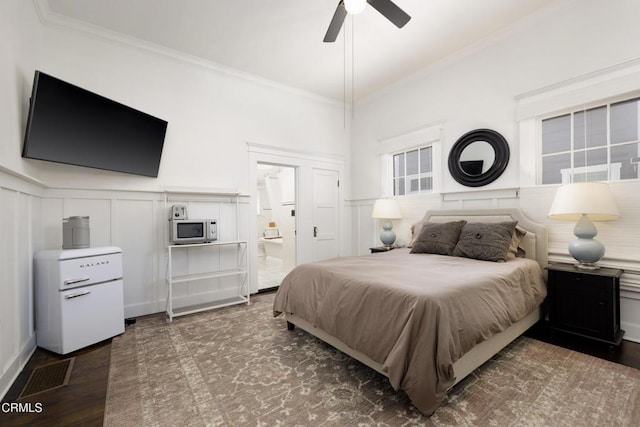 bedroom featuring ornamental molding, dark wood-type flooring, ensuite bathroom, and ceiling fan