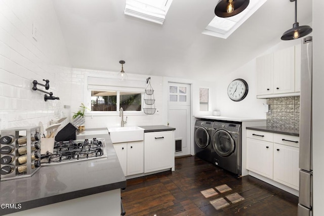 kitchen featuring white cabinetry, sink, vaulted ceiling with skylight, and independent washer and dryer