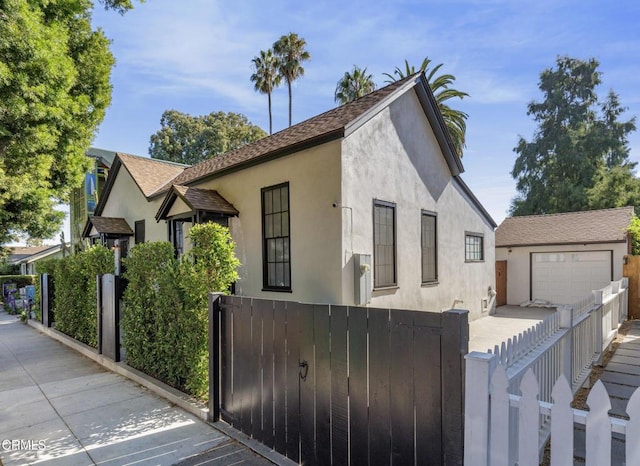 view of front of home with a fenced front yard, an outdoor structure, and stucco siding
