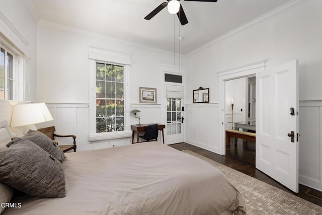 bedroom with a decorative wall, a ceiling fan, crown molding, wood finished floors, and a wainscoted wall