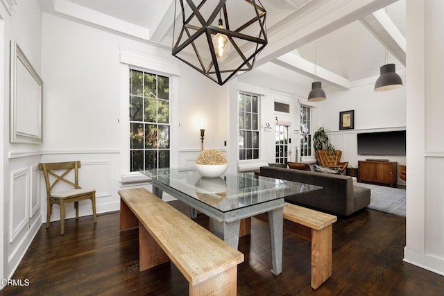 dining area with a decorative wall, beam ceiling, wainscoting, and dark wood finished floors
