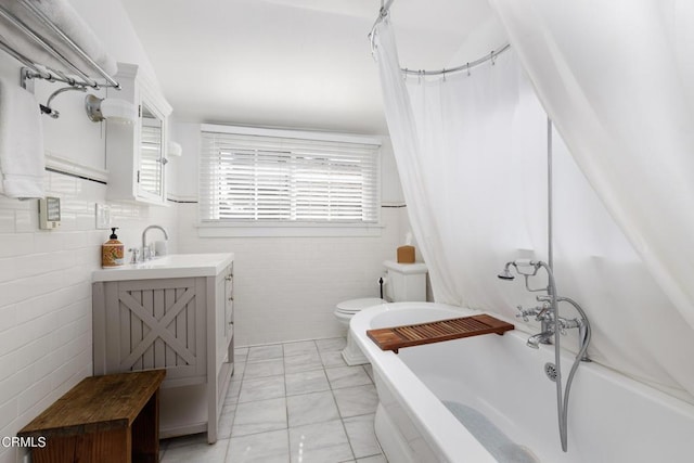 bathroom with tile walls, toilet, marble finish floor, and a healthy amount of sunlight
