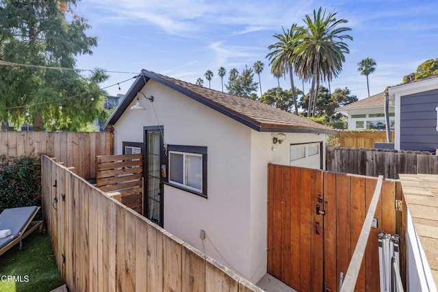 view of home's exterior featuring roof with shingles, fence, and stucco siding
