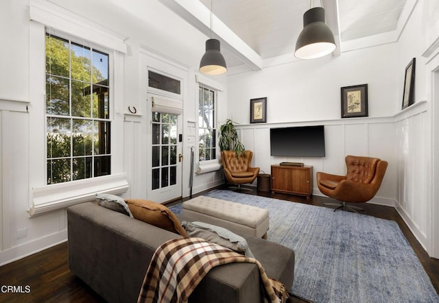 living room with a decorative wall, baseboards, beamed ceiling, and dark wood finished floors