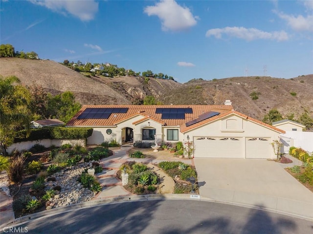 mediterranean / spanish home featuring a garage, concrete driveway, a mountain view, and stucco siding