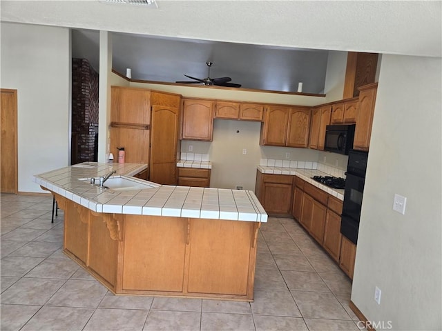 kitchen with light tile patterned floors, tile counters, sink, and black appliances