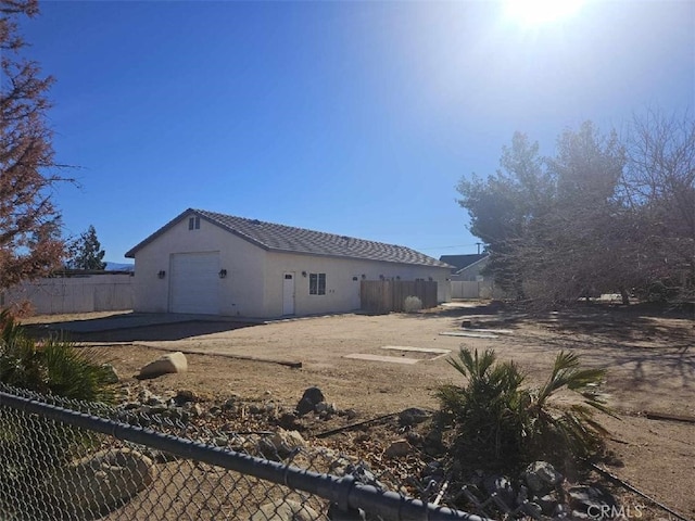 back of house with an outbuilding, fence, a garage, and stucco siding