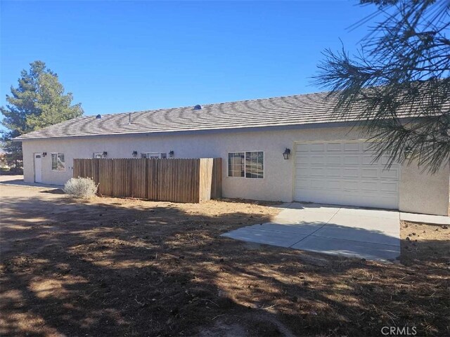 back of house with a garage, fence, and stucco siding