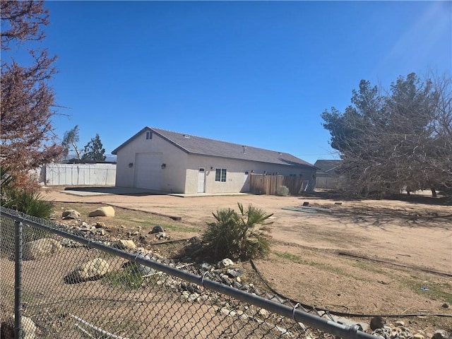 exterior space with a garage, fence, and stucco siding