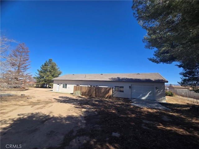 rear view of property featuring fence and stucco siding