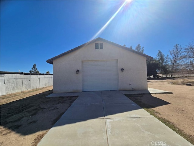 detached garage with fence and concrete driveway