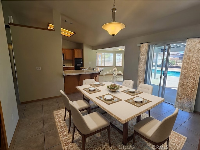 tiled dining area featuring lofted ceiling and baseboards