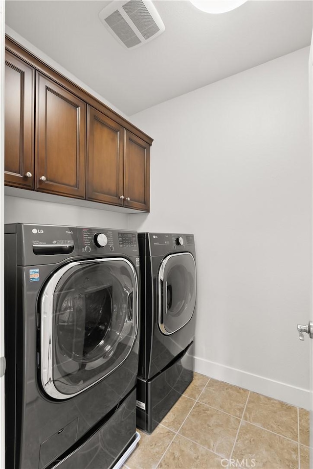 laundry room with washer and clothes dryer, cabinets, and light tile patterned flooring