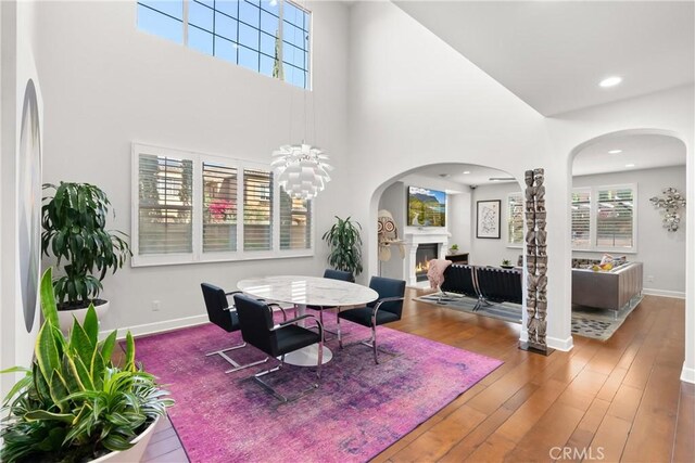 dining space with a towering ceiling, hardwood / wood-style floors, and an inviting chandelier