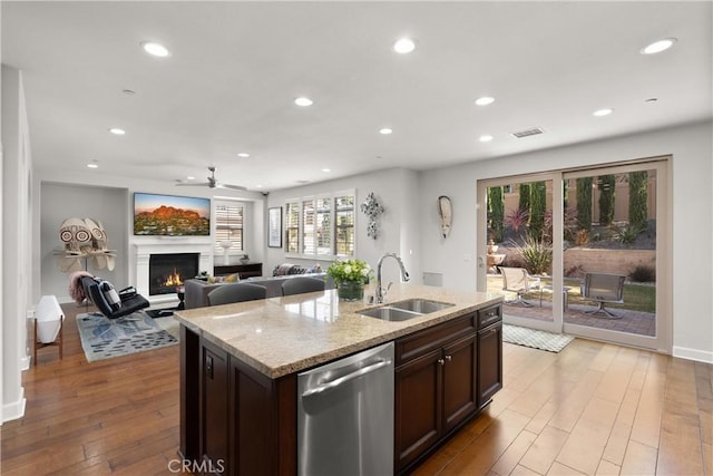 kitchen featuring sink, stainless steel dishwasher, a kitchen island with sink, and light hardwood / wood-style floors