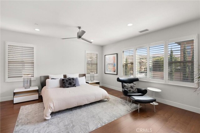 bedroom featuring ceiling fan, dark hardwood / wood-style floors, and multiple windows