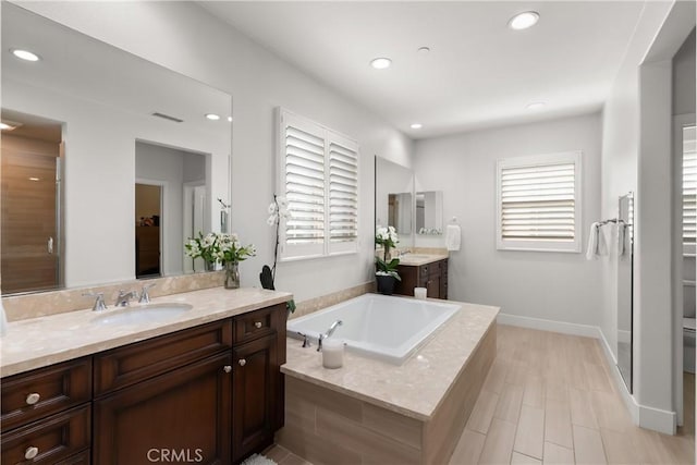 bathroom with recessed lighting, a sink, and a healthy amount of sunlight