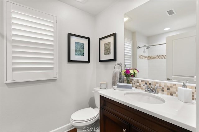 bathroom featuring vanity, tiled shower, toilet, and decorative backsplash