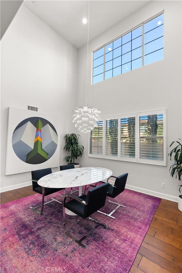 dining area with a towering ceiling and dark hardwood / wood-style flooring