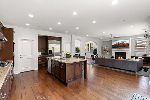 kitchen with appliances with stainless steel finishes, dark hardwood / wood-style floors, sink, a breakfast bar area, and a center island with sink