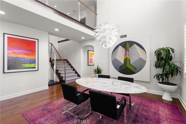 dining room with a towering ceiling, dark hardwood / wood-style flooring, and a chandelier