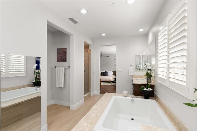 bathroom featuring vanity, wood-type flooring, a healthy amount of sunlight, and separate shower and tub