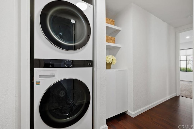 laundry room featuring stacked washer and dryer and dark hardwood / wood-style floors