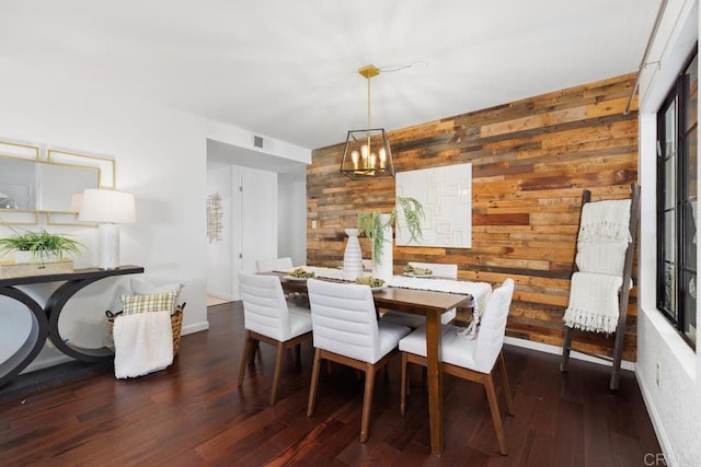 dining space featuring dark hardwood / wood-style flooring, a notable chandelier, and wooden walls