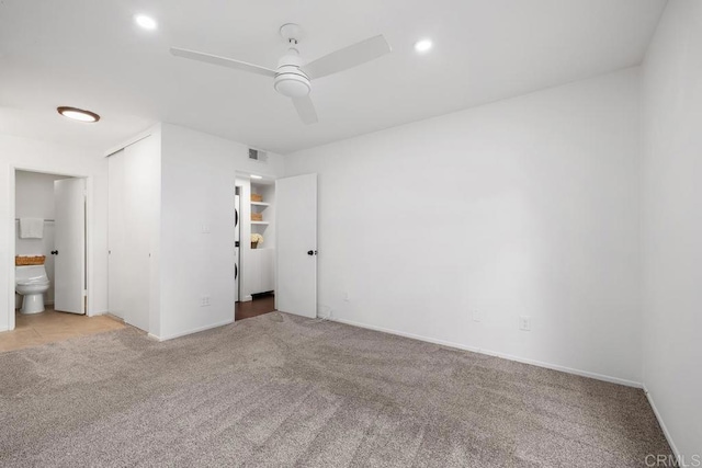 unfurnished bedroom featuring ceiling fan, connected bathroom, a closet, and light carpet